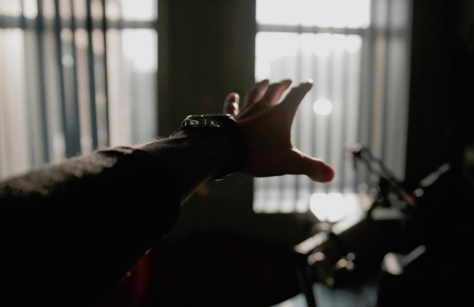 Man, showing hand, near the windows with light, among the dakness