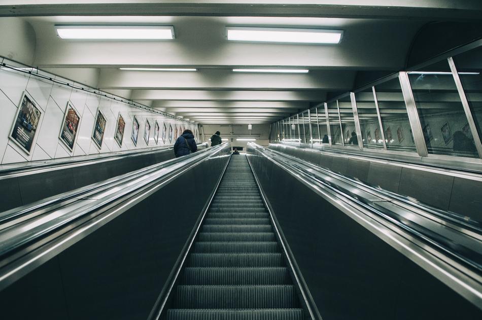 Interior of the building with people on escalator, in lights