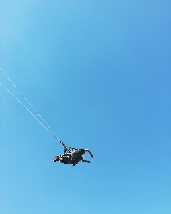 Man, flying on the parachute, in sunlight, under the blue sky