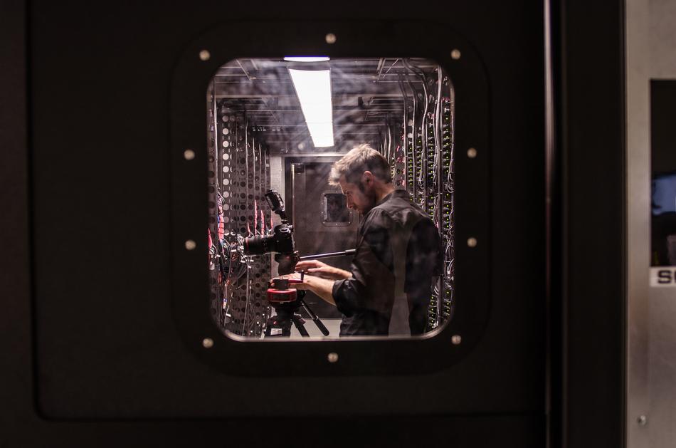 View of the man, wit the camera, on the tripod, through the glass, with lights