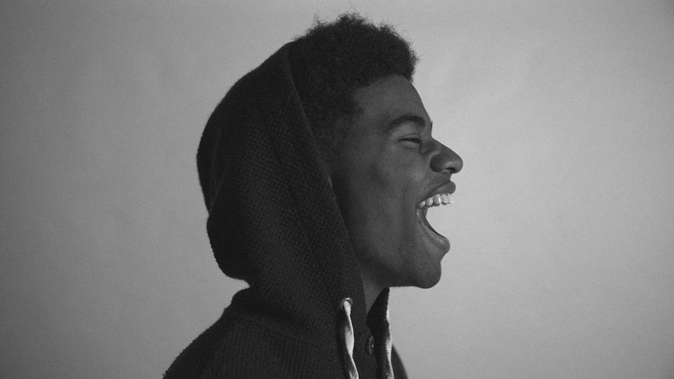 Black and white profile portrait of the laughing guy, in the hoodie