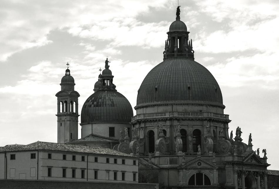 Black and white photo of the beautiful church with dome, under the sky with clouds, in Venice, Italy