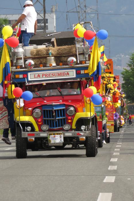 People at the colorful parade with the cars, on the road in Medellin, Colombia, in sunlight