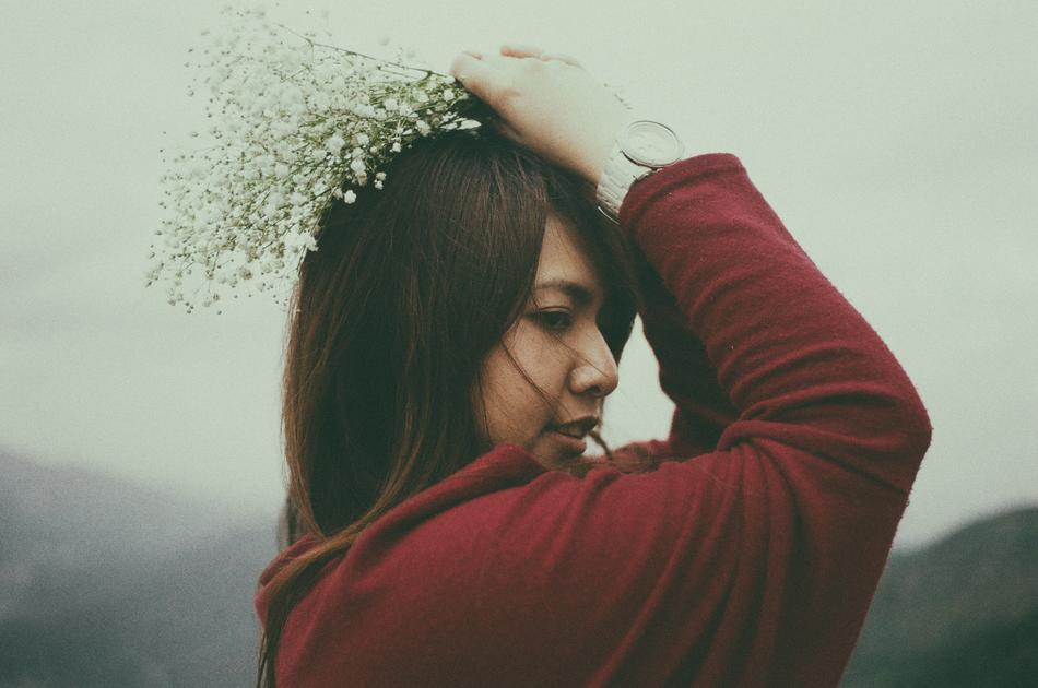 young asian woman with flowers in hand at head, blur background