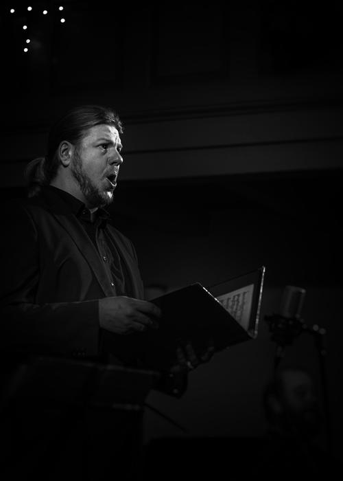 man with music sheet in hands sings at darkness