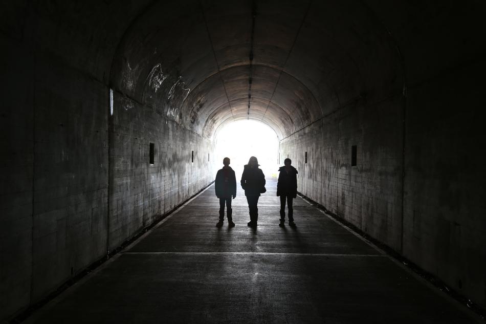 three persons in dark Tunnel, backlight