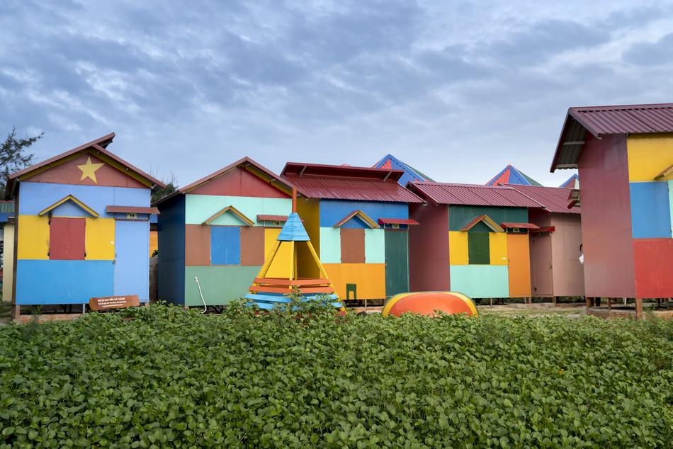 Colorful huts with images, near the green grass, under the sky with clouds