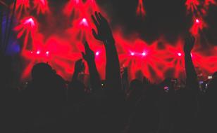 black silhouettes of crowd wearing red spotlights at a concert