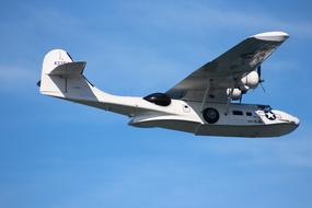 a military plane flies in the blue sky