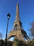 Beautiful landscape with Eiffel Tower, near the lantern, among the colorful plants, in Paris, France, under the blue sky