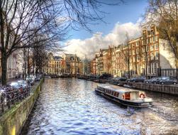Beautiful landscape of Amsterdam, with the canal with boat, among the buildings and trees