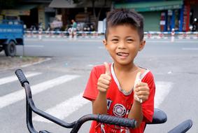 happy asian child boy thumbs up in city