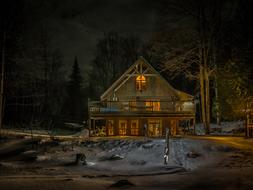 Beautiful landscape with the house with lights, among the trees, at darkness