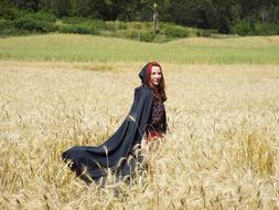 a pretty girl with a cape in a field