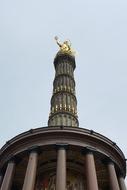 a golden tower with a sculpture and a house