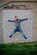 young man jumping near the old wall