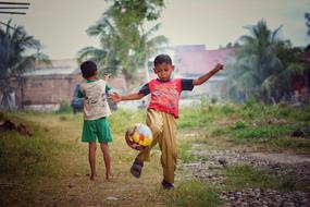 two asian Boys play soccer outdoor