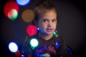 Portrait of the cute girl, among the colorful Christmas bokeh lights