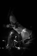 Portrait of the girl in glasses, near the lights, among the darkness