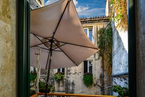 Umbrella among the old, colorful buildings with plants, in Croatia