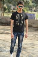 Young man in t-shirt, jeans and sunglasses, near the fence