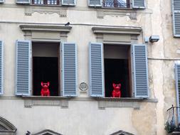 red sculptures of dogs on the window of a building in Florence, Italy