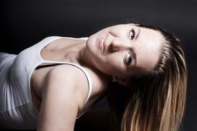 Portrait of the smiling, laying girl, in white clothing, in light