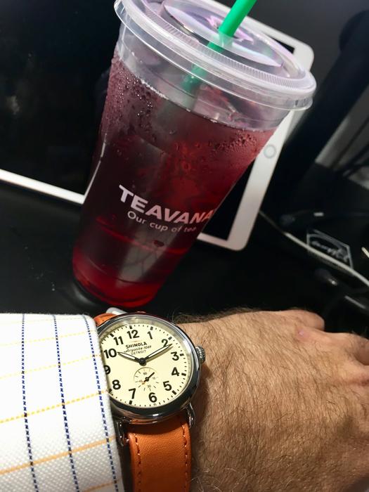 classic wristwatch on male hand near plastic cup with drink
