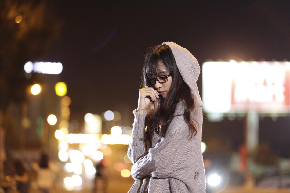 Beautiful girl with the glasses and hood, on the street with the colorful lights, at the night