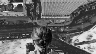 girl looks from a high-rise at city traffic