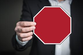 Man in suit, holding red and white sign, in the hand