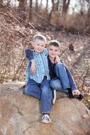 happy brothers on a big stone in nature