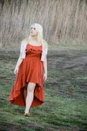 a girl in a red dress walks in an autumn meadow