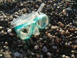 swimming mask lies on pebbles on the beach