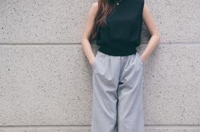 Girl in black Shirt and grey trousers standing at wall