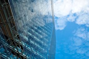 Low angle shot of the shiny glass building in DÃ¼sseldorf, Germany, under the blue sky with white clouds