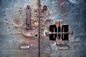 Close-up of the old, rusty, damaged door with the lock and hole