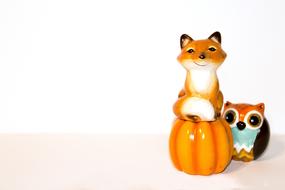 ceramic figurine of a fox on a pumpkin and an owl