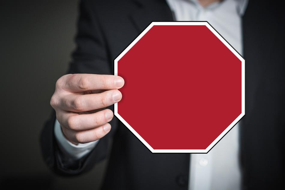 Man in suit, holding red and white sign, in the hand