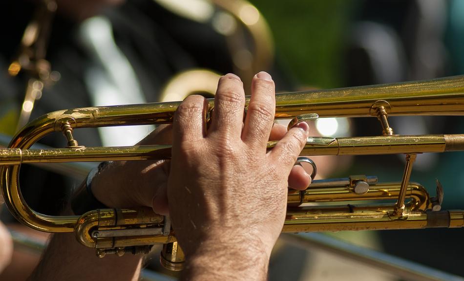 Person playing on a shiny trumpet
