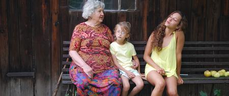 grandmother with girls on a bench near the house