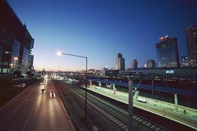 Cityscape with the cars on the road, among the city with lights, in the evening