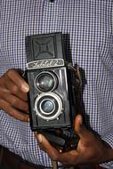 Man, holding shiny, vintage, old camera in the hands