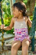 Smiling child in colorful dress swinging