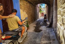 guy and a girl on a scooter on a narrow street