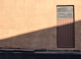 Brown door in the wall in light and shadow