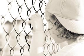 child waiting near the wire fence