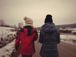 two girls walking away on road