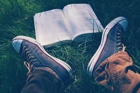 feet near an open book on the grass