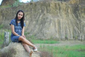stylish girl posing on a large stone on a blurred background